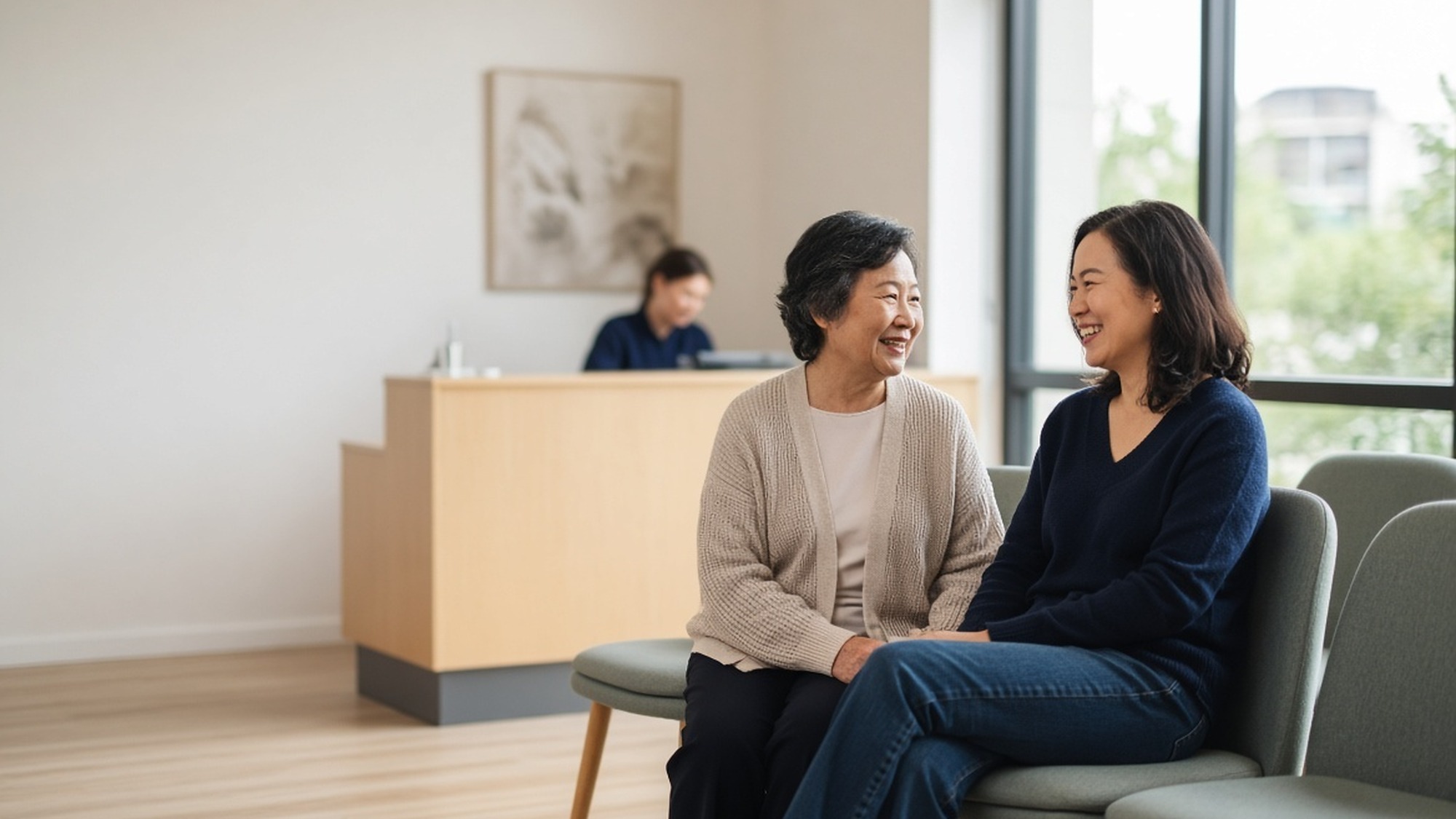 Two women talking in a waiting room with a reception desk behind them