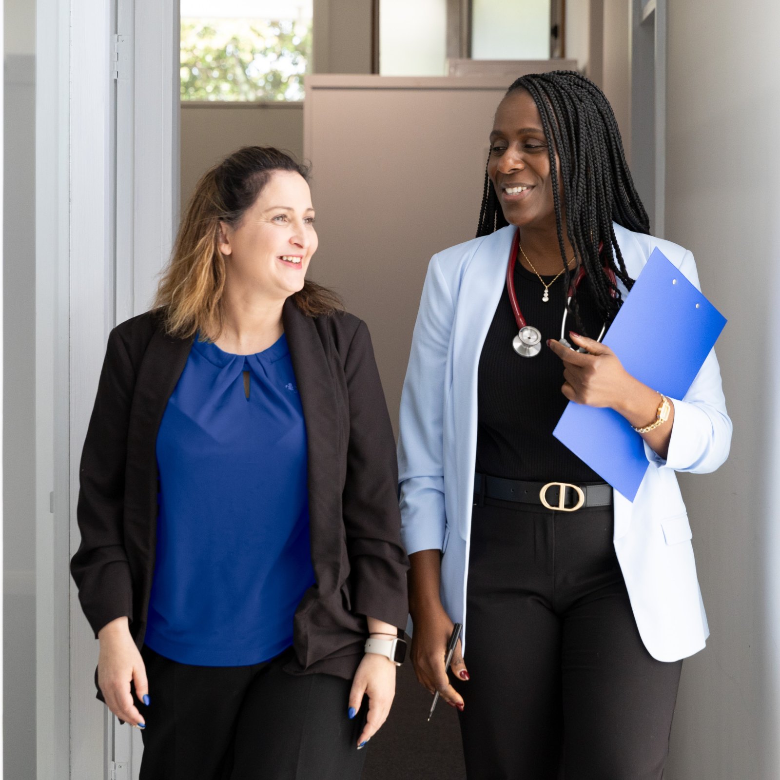 Dr Tolu laughing with a colleague as they walk down the practice corridor